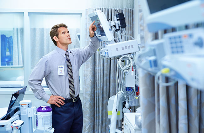 A man in a hospital room looking at medical equipment.