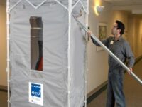 A man is holding the poles to move a portable shower.