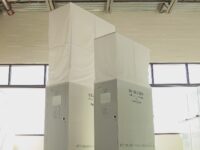 Two white boxes on wheels in a room.