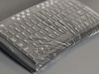 A keyboard wrapped in plastic on top of a table.